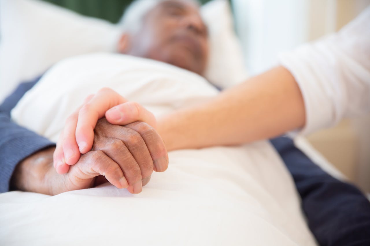 about-us A comforting gesture as a hand holds another in a hospital setting, symbolizing care and support.